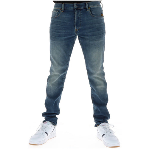 Image 1 : Jean slim G-Star homme en denim bleu effet usé porté avec des sneakers blanches Lacoste, vue frontale — Delvale