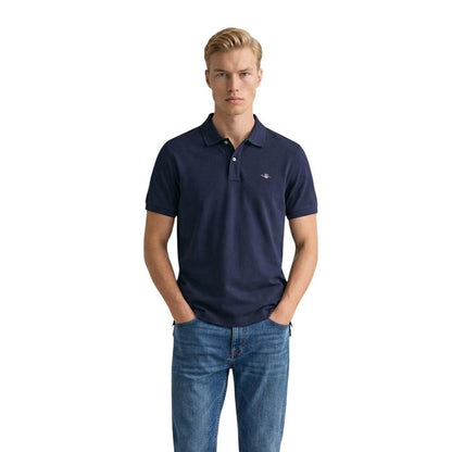 Image 1 : Homme portant le polo piqué Gant Shield bleu marine à manches courtes avec un jean brut, vue de face — Delvale
